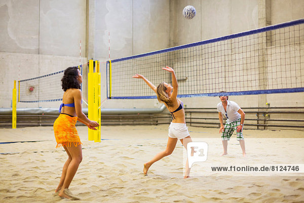 Friends playing indoor beach volleyball