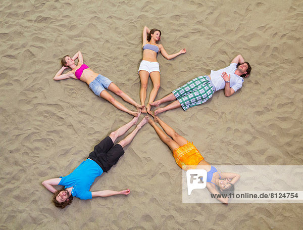 Luftaufnahme von sternförmig auf Sand liegenden Freunden