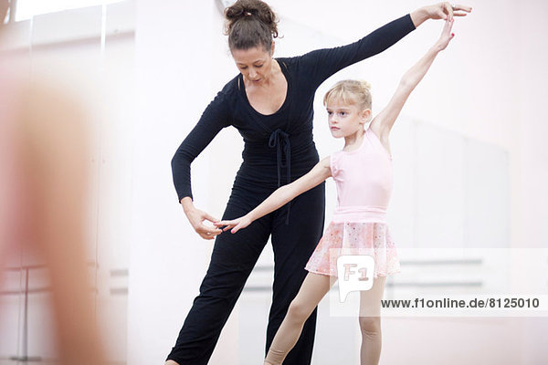 Young ballerina practicing pose with teacher