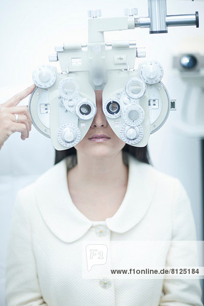 Junge Frau mit Sehtest beim Optiker