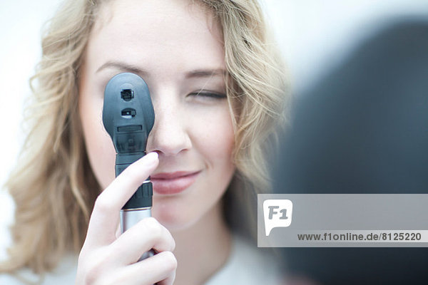 Close up of optician looking through ophthalmoscope