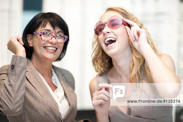 Two women laughing whilst trying on eyeglasses
