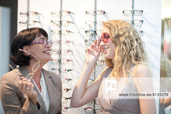 Two women trying on eyeglasses in opticians shop