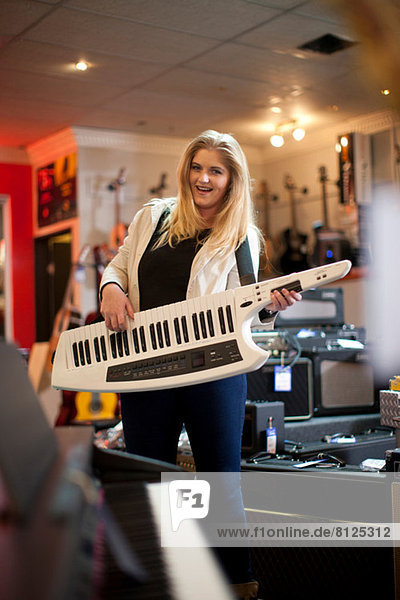 Junge Frau spielt Keytar im Musikladen