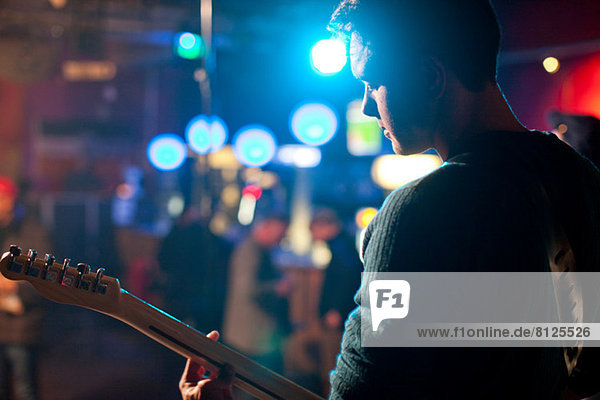 Mann auf der Bühne spielt Gitarre im Nachtclub