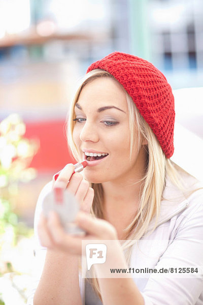 Junge Frau in roter Strickmütze mit Lippenstift