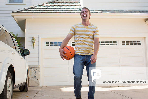 Young man holding basketball laughing  portrait