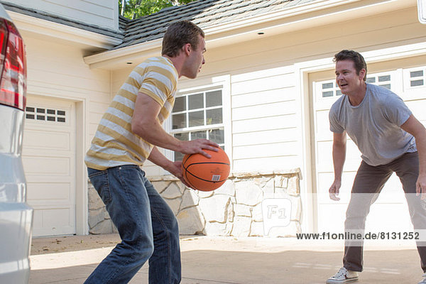 Father and adult son playing basketball