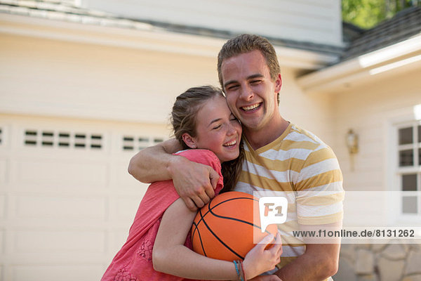 Brother with arm around sister holding basketball