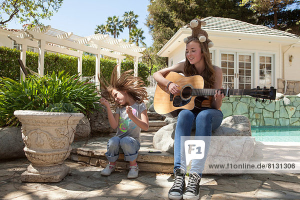 Mädchen mit älterer Schwester beim Gitarrespielen