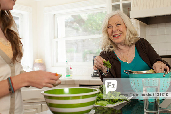 Enkelin mit Großmutter bei der Zubereitung von Salat