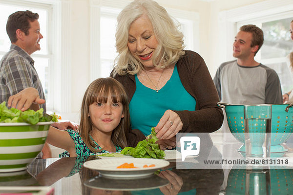Enkelin und Großmutter bei der Zubereitung des Salats