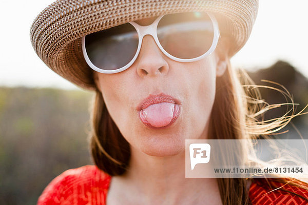 Reife Frau mit Sonnenbrille und herausstehender Zunge
