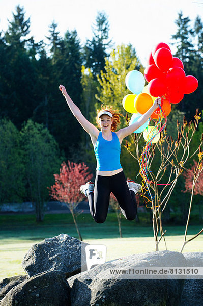 Teenagermädchen hält Luftballons  die in der Luft springen