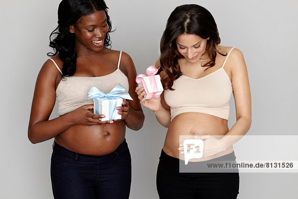 Zwei schwangere Frauen mit rosa und blauen Geschenkschachteln
