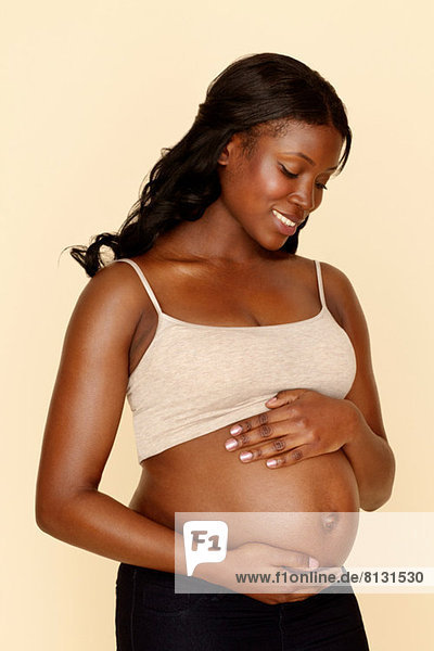 Schwangere junge Frau  die den Bauch berührt.