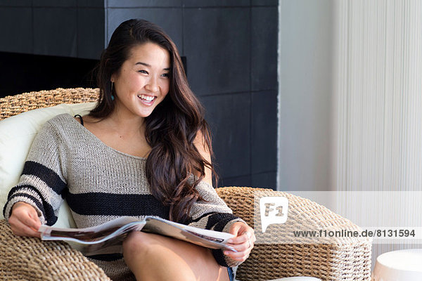 Porträt einer jungen Frau auf einem Sessel mit Magazin