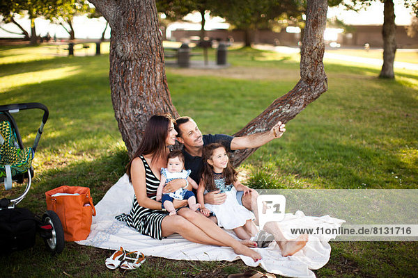 Familie mit zwei Kindern auf Picknickdecke sitzend