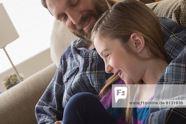Vater und Tochter lächeln auf der Couch
