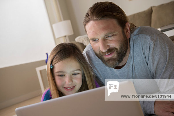 Vater und Tochter schauen auf den Laptop