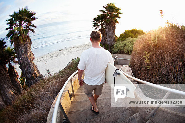Surfer geht die Treppe hinunter zum Strand