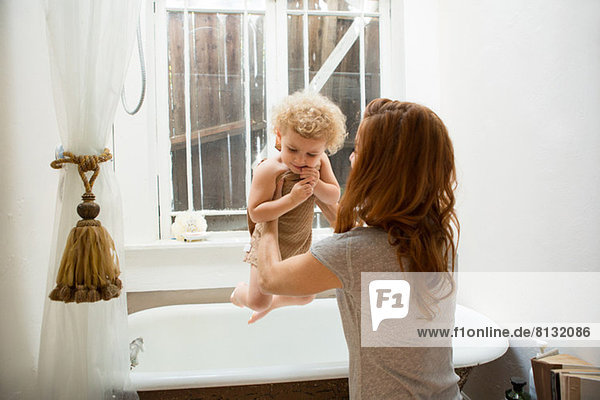 Mother lifting child from bathtub