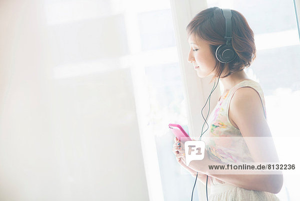 Frau hört Musik auf dem Handy mit Kopfhörer
