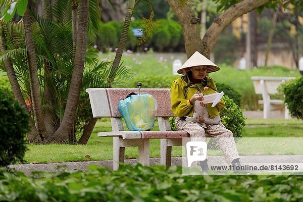 Vietnamese Woman having a Snack in a Park in Hanoi  Vietnam.