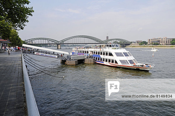 Tour boat at a dock on the bank of the Rhine River  Hohenzollern Bridge