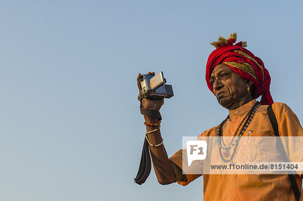 Sadhu  heiliger Mann  macht Fotos beim Shahi Snan  dem königlichen Bad  während des Kumbha Mela Festivals