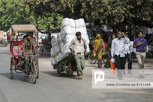 Fahrrad-Rikscha und ein Mann  der Waren auf einem Handwagen transportiert  Khari Baoli Road