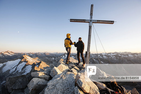 Mountain climbers on the summit cross of Reichenspitze Mountain  3303m  Zillertal Alps