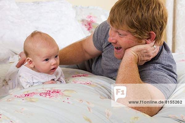 Father and son lying on bed  smiling