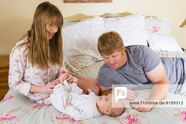 Parents with baby boy on bed  smiling