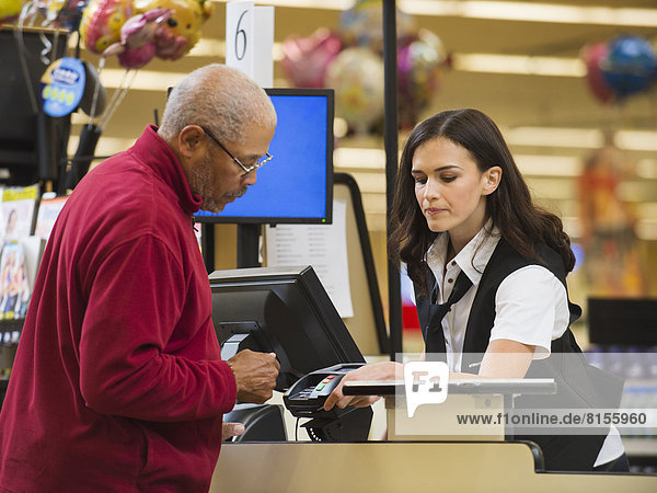 Cashier and customer at grocery store checkout