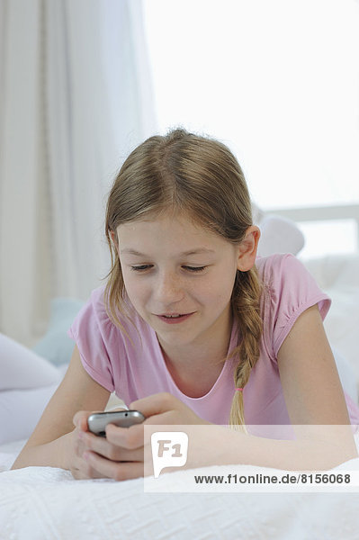 Girl using smart phone on bed  smiling