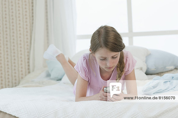 Mädchen mit Smartphone im Bett