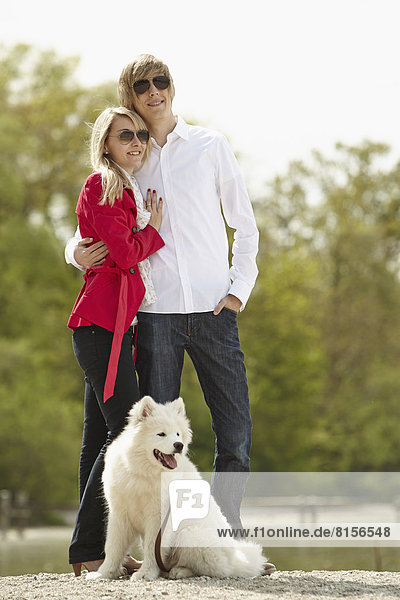 Deutschland  Junges Paar stehend mit Hund  lächelnd