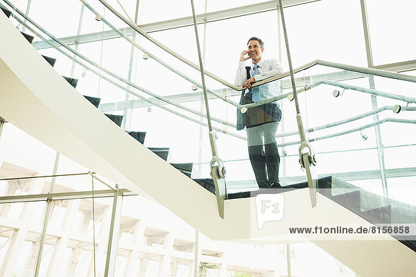 Caucasian businessman on cell phone on office staircase