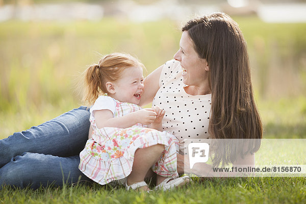 Caucasian mother and baby relaxing in grass