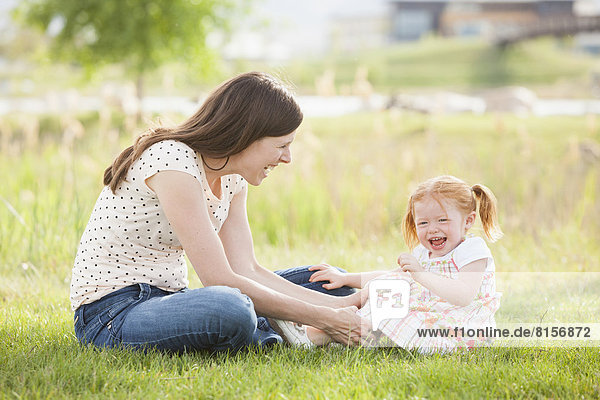 Caucasian mother and daughter playing in grass