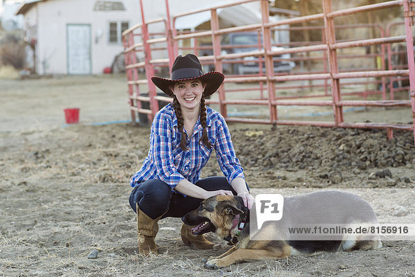Caucasian girl petting dog on farm