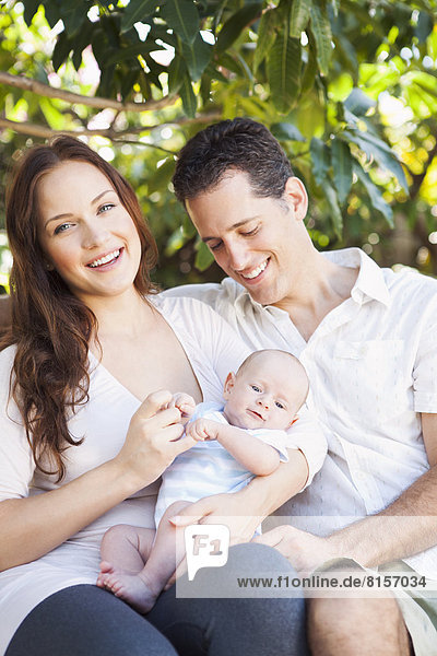 Caucasian couple holding baby outdoors