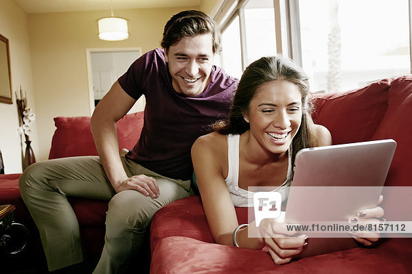 Couple using tablet computer on sofa