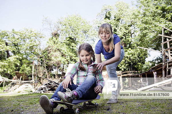 Germany  North Rhine Westphalia  Cologne  Mother and daughter playing with skateboard