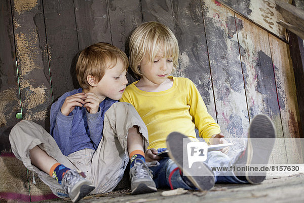Germany  North Rhine Westphalia  Cologne  Boys using digital tablet in playground