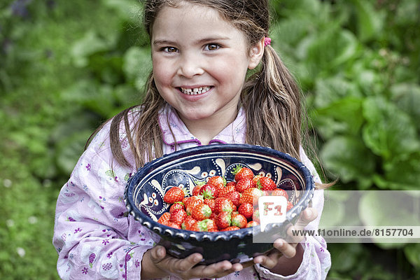 Deutschland  Nordrhein-Westfalen  Köln  Portrait eines Mädchens mit einer Schale Erdbeeren  lächelnd