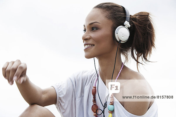 Deutschland  Junge Frau hört Musik mit Kopfhörern  lächelt