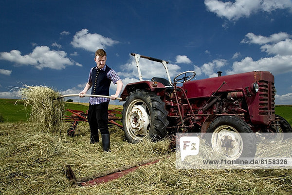 Germany  Bavaria  Farmer with rake in field