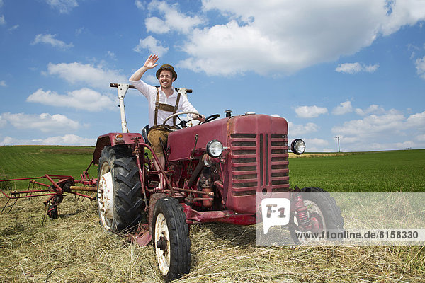 Germany  Bavaria  Farmer in tractor and waving  smiling